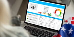 Person viewing a laptop displaying a credit score dashboard and financial report.